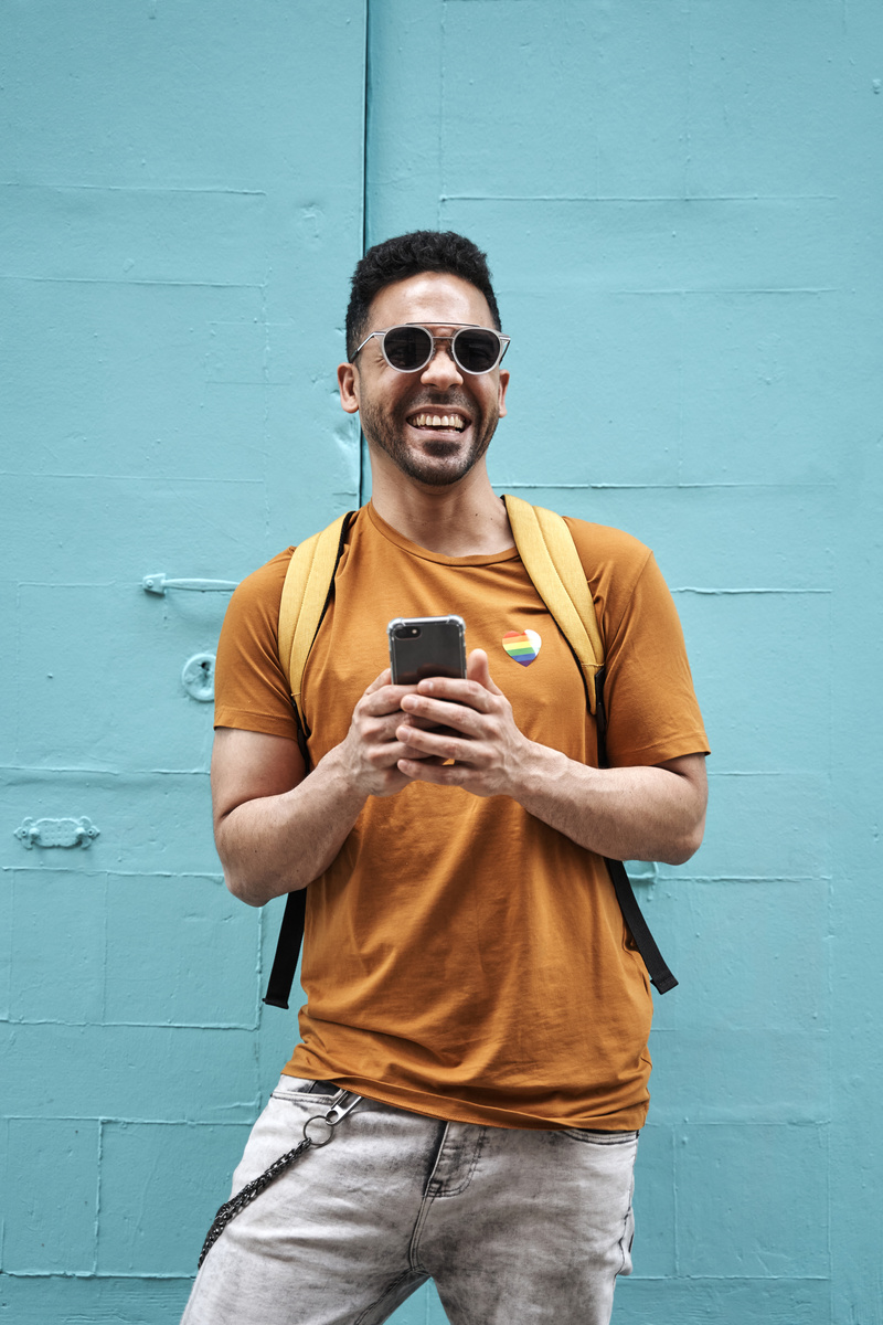 Latino Man with Backpack Holding Phone Outdoors
